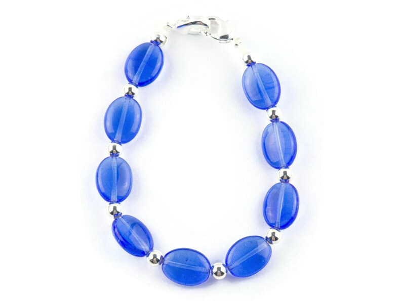 May include: A blue glass bead bracelet with silver accents. The bracelet is made with oval-shaped beads and a silver clasp.