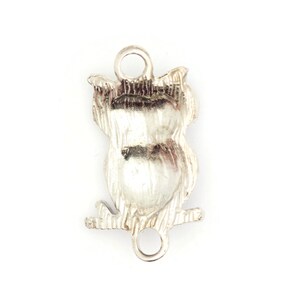 May include: Silver owl charm with a detailed design. The charm has two loops for attaching to a bracelet or necklace.