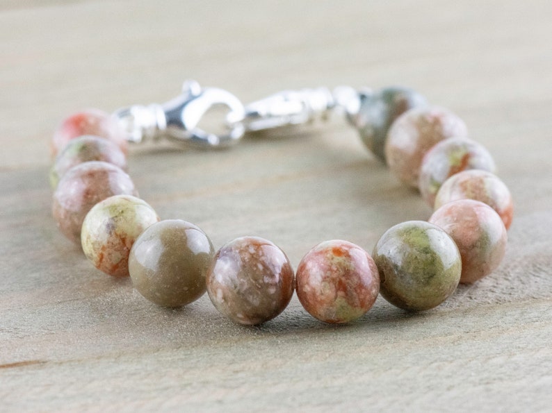 Pu&ograve; includere: Un braccialetto di perline con perline rotonde multicolori nei toni del verde, marrone e rosso. Il braccialetto ha una chiusura color argento. Le perline hanno un diametro di circa 2 cm.