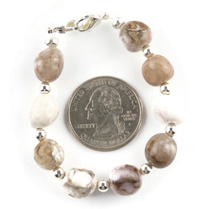 May include: A bracelet made with brown and white agate beads and silver spacer beads. The bracelet is approximately the size of a US quarter.