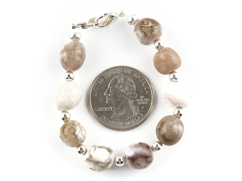 May include: A bracelet made with brown and white agate beads and silver spacer beads. The bracelet is approximately the size of a US quarter.