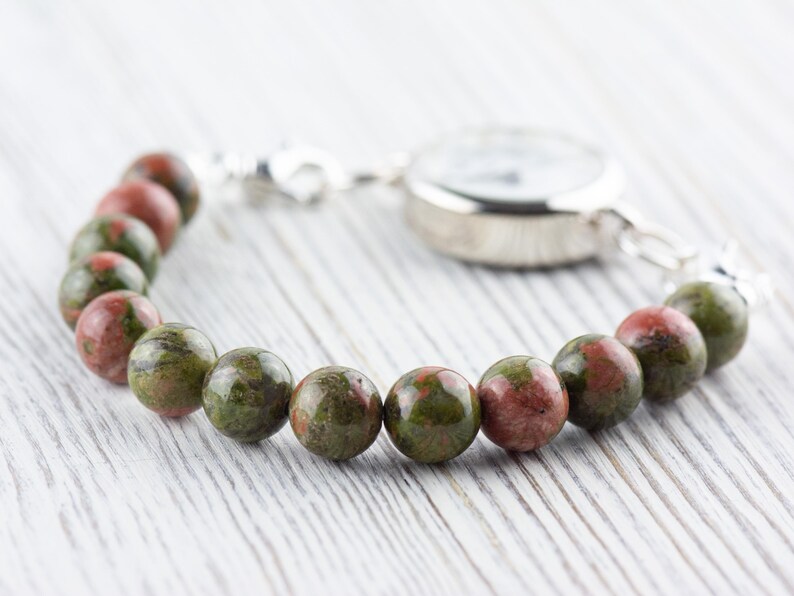 Puede incluir: Un reloj plateado con una pulsera de piedra moteada de verde y rojo.