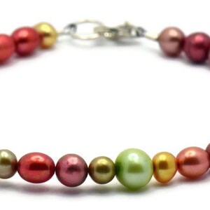 Pu&ograve; includere: Un braccialetto di perle multicolori con una chiusura argentata. Le perle sono in tonalit&agrave; di rosa, rosso, oro e verde.