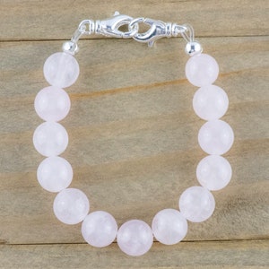 Puede incluir: Un brazalete de cuentas de cuarzo rosa con cierre de plata.