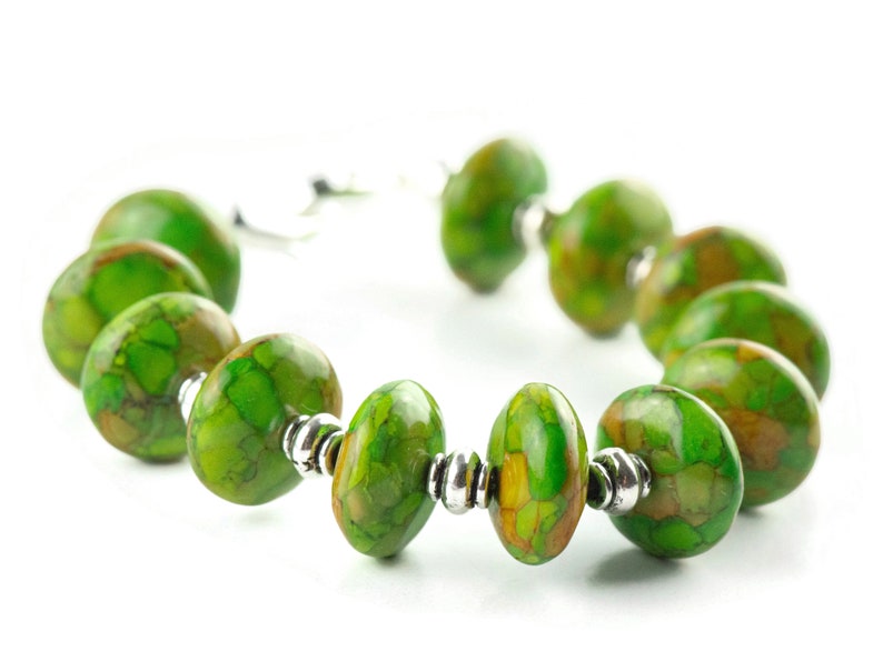 Pode incluir: Um bracelete de pedra verde e marrom com contas de prata. O bracelete &eacute; feito de pedras ovais com um padr&atilde;o de m&aacute;rmore.