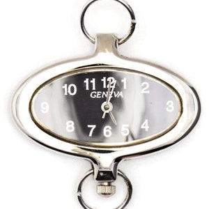 May include: A silver oval-shaped pocket watch with a key ring attached. The watch face has black Roman numeral hour markers and the word "GENEVA" printed on it.