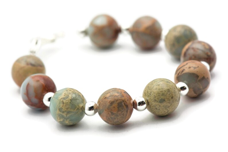May include: A bracelet made of brown, green, and white marbled beads with silver accents.
