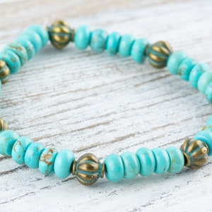 May include: A turquoise and gold beaded bracelet with a simple design. The bracelet is made with small, round turquoise beads and gold accent beads.