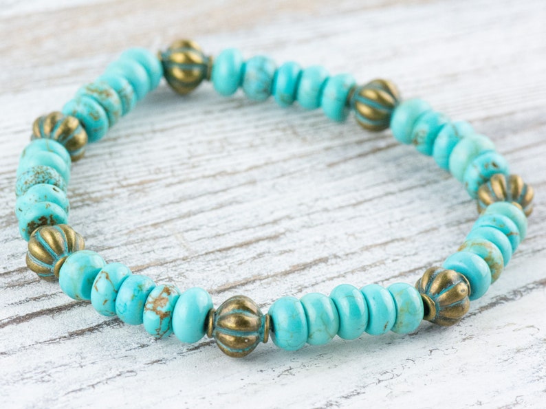 May include: A turquoise and gold beaded bracelet with a simple design. The bracelet is made with small, round turquoise beads and gold accent beads.