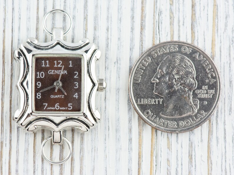 May include: A silver-toned watch with a square face and a brown dial. The watch is about the size of a US quarter. The watch face has black numbers and hands, and the words "GENEVA" and "QUARTZ" are printed on the dial.