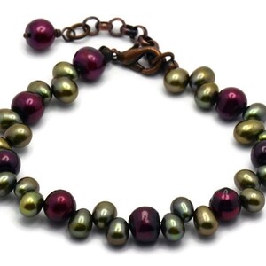 May include: A bracelet made of green and burgundy freshwater pearls with a copper clasp.
