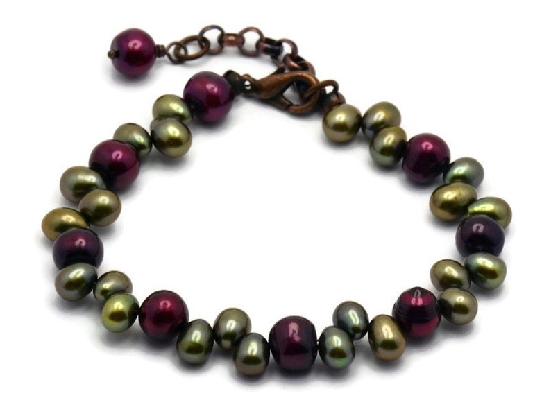 May include: A bracelet made of green and burgundy freshwater pearls with a copper clasp.