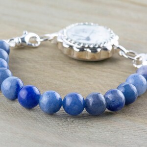 May include: A silver watch with a white face and a blue gemstone beaded bracelet.