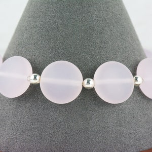 May include: A bracelet made of frosted pink glass beads and silver spacers.