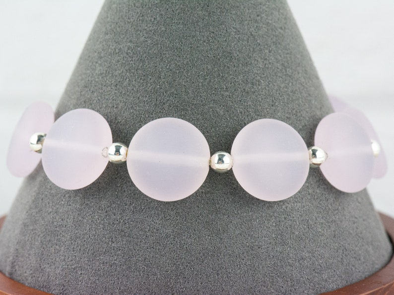May include: A bracelet made of frosted pink glass beads and silver spacers.