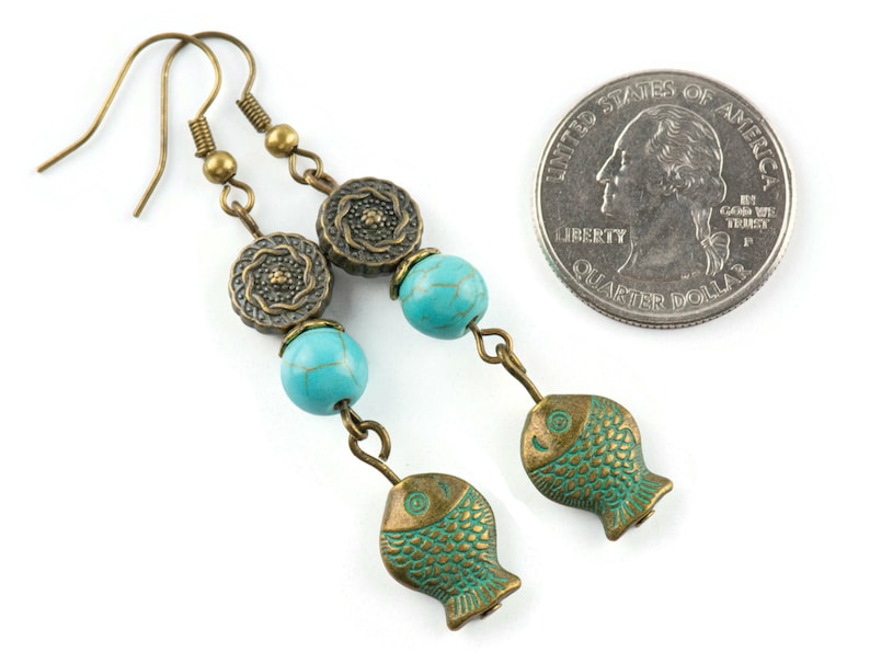 May include: Turquoise and bronze dangle earrings with a fish charm and a turquoise bead. The earrings are about the size of a quarter.
