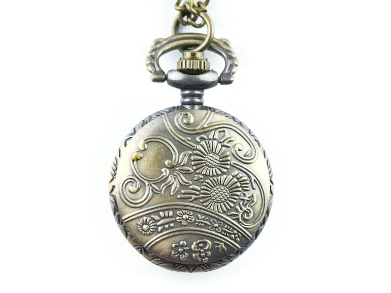 May include: A gold and silver pocket watch with a floral design on the face. The watch has a chain attached to it.