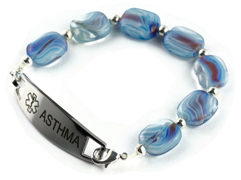 May include: A medical alert bracelet with a silver tag that reads "ASTHMA" and a star of life symbol. The bracelet is made of blue and white glass beads.