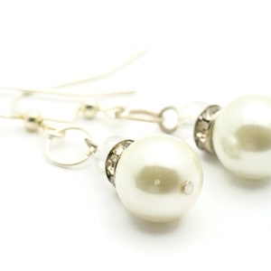Peut inclure: Une paire de boucles d'oreilles en argent avec une perle et des accents de cristal.