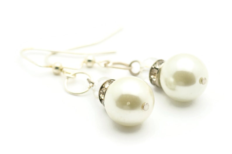 Peut inclure: Une paire de boucles d'oreilles en argent avec une perle et des accents de cristal.