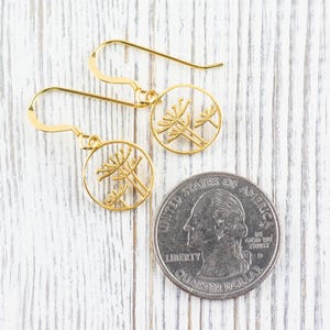 May include: A pair of gold earrings with a delicate floral design. The earrings are made of a thin metal and have a simple, elegant style.