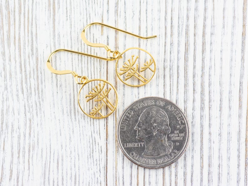 May include: A pair of gold earrings with a delicate floral design. The earrings are made of a thin metal and have a simple, elegant style.