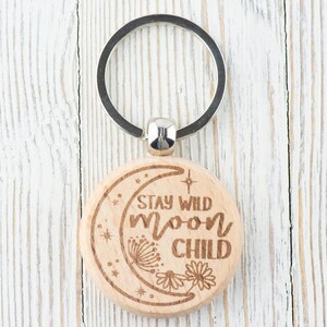 May include: Wooden keychain with a crescent moon design and the text "Stay Wild Moon Child".