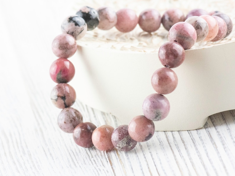 May include: A pink and gray gemstone bracelet with round beads. The bracelet is made of natural stones and is a beautiful accessory for any occasion.