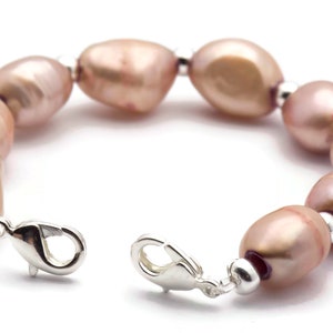 May include: A bracelet made of pink freshwater pearls and silver metal. The bracelet has a lobster clasp closure.