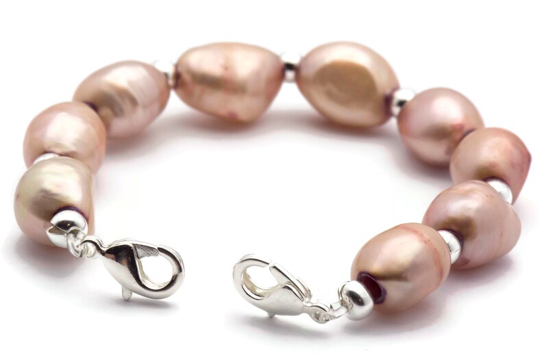 May include: A bracelet made of pink freshwater pearls and silver metal. The bracelet has a lobster clasp closure.
