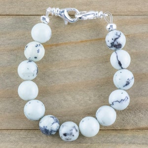 Peut inclure: Un bracelet en pierre blanche et noire mouchet&eacute;e avec un fermoir argent&eacute;.