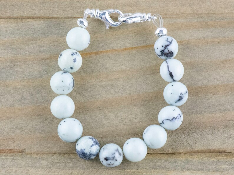 Peut inclure: Un bracelet en pierre blanche et noire mouchet&eacute;e avec un fermoir argent&eacute;.