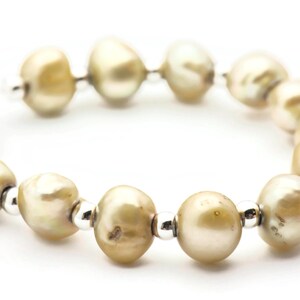 以下が含まれることがあります： シルバーのアクセントが付いたパールブレスレット。パールは薄いベージュ色で、シルバービーズで繋げられています。