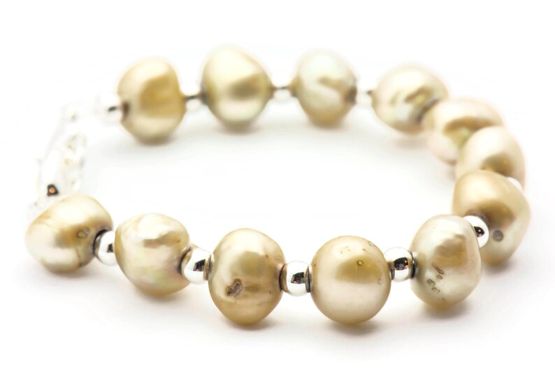 以下が含まれることがあります： シルバーのアクセントが付いたパールブレスレット。パールは薄いベージュ色で、シルバービーズで繋げられています。