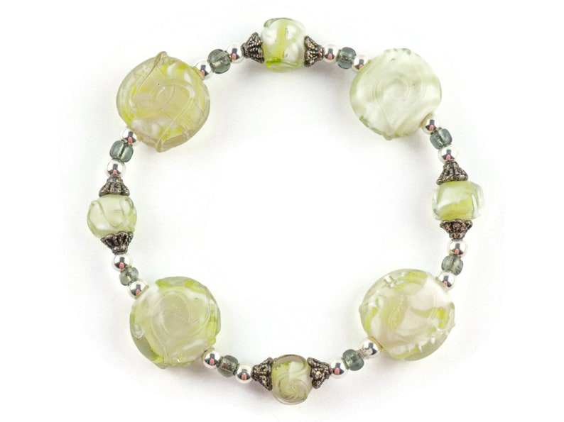 Peut inclure: Un bracelet en verre vert avec des motifs floraux grav&eacute;s et des accents argent&eacute;s.