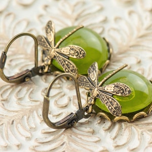 May include: A pair of green glass and bronze dragonfly earrings. The earrings feature a detailed dragonfly design with a green glass cabochon in the center.