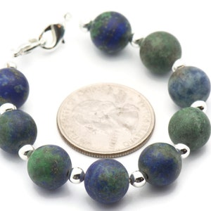 May include: A bracelet made with alternating blue and green gemstone beads. The beads are round and have a mottled appearance. The bracelet has a silver clasp.