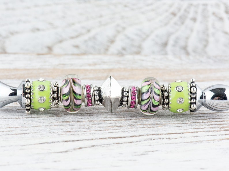 Peut inclure: Un bracelet &agrave; breloques argent&eacute; avec des perles en verre vertes et roses, un charme argent&eacute; et des entretoises argent&eacute;es.