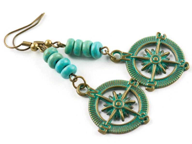 May include: Turquoise blue and bronze compass earrings with a beaded dangle. The compass features a starburst design with the cardinal directions marked.