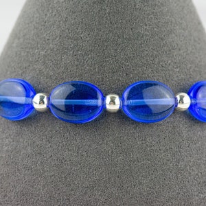 May include: A blue glass bead bracelet with silver spacer beads. The bracelet is on a gray background.