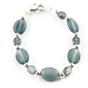 Pu&ograve; includere: Un braccialetto con perline ovali e sfaccettate nei toni del verde acqua e grigio, intervallate da piccole perline color argento. Il braccialetto &egrave; assicurato con una chiusura argentata, che mostra un design delicato ed elegante.