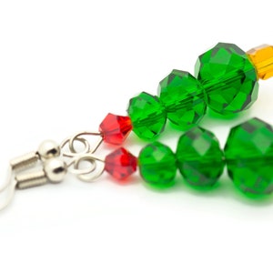 May include: A pair of green, red, and orange crystal Christmas tree earrings with silver hooks.