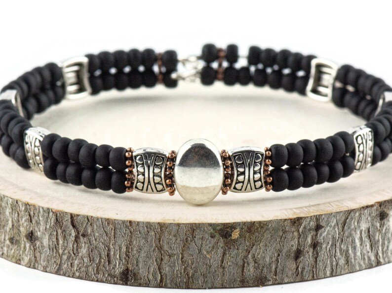 Button and Bows Jet Black Cuff Memory Wire Bracelet on a wood piece with tree bark edging