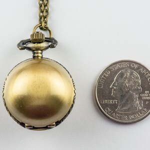 May include: A gold-toned pocket watch with a chain, the watch is about the size of a quarter.