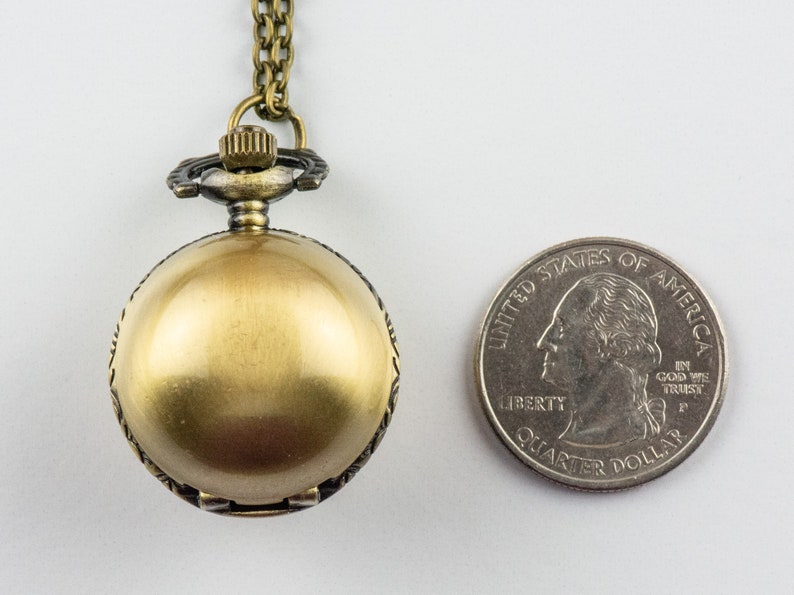 May include: A gold-toned pocket watch with a chain, the watch is about the size of a quarter.
