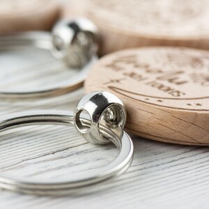 May include: A wooden keychain with a crescent moon design and the text "To the moon and back". The keychain is attached to a silver key ring.