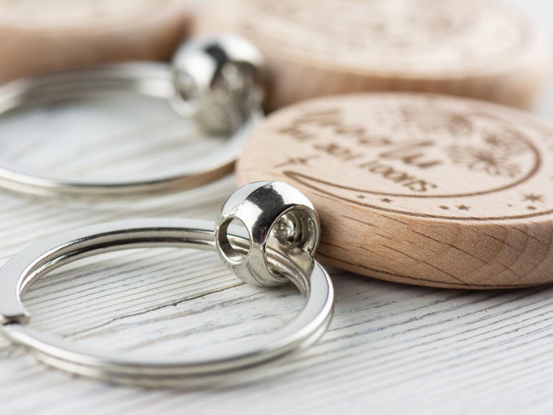 May include: A wooden keychain with a crescent moon design and the text "To the moon and back". The keychain is attached to a silver key ring.