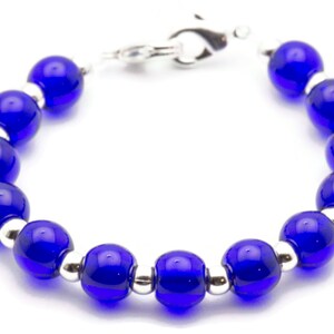 May include: A blue glass bead bracelet with silver accents. The bracelet has a clasp closure.