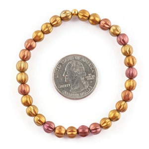 May include: A gold and copper toned beaded bracelet with a textured finish. The bracelet is approximately the size of a US quarter.