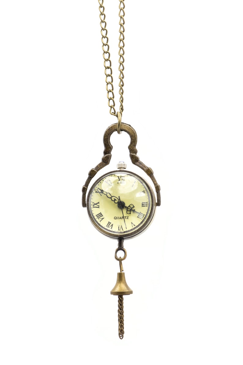 May include: A gold-toned pocket watch necklace with Roman numeral markings on the face. The watch has a quartz movement and is attached to a delicate chain with a bell-shaped pendant.